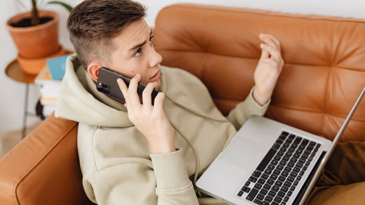 Parent and teenager sitting side by side on a sofa, each holding their own phone.