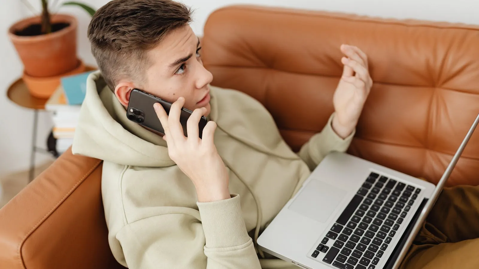 Parent and teenager sitting side by side on a sofa, each holding their own phone.